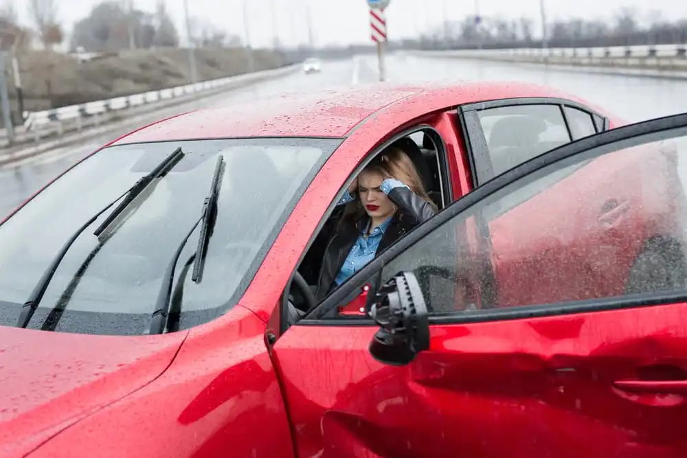 Anxious young woman in a car, feeling unwell after a car crash. Dealing with the aftermath of an accident.