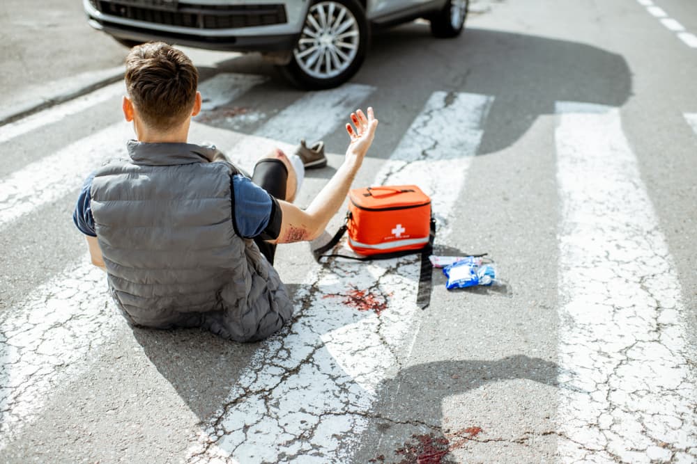 Startled and injured man assessing wounds, awakening on a pedestrian crossing after a car accident.