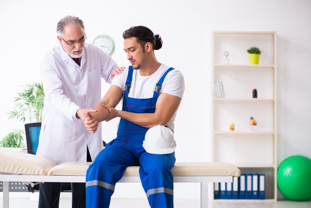 Young male contractor consulting with senior doctor during medical appointment.