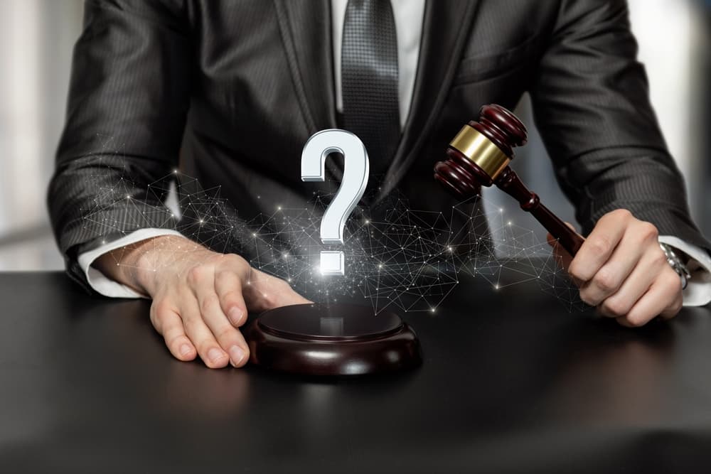 A car accident lawyer with a gavel in hand stands over a table featuring a question mark