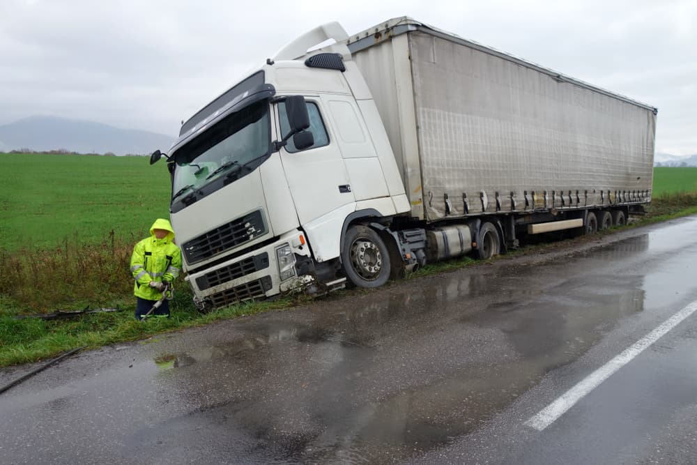 The truck lies in a ditch after the road accident over raining day