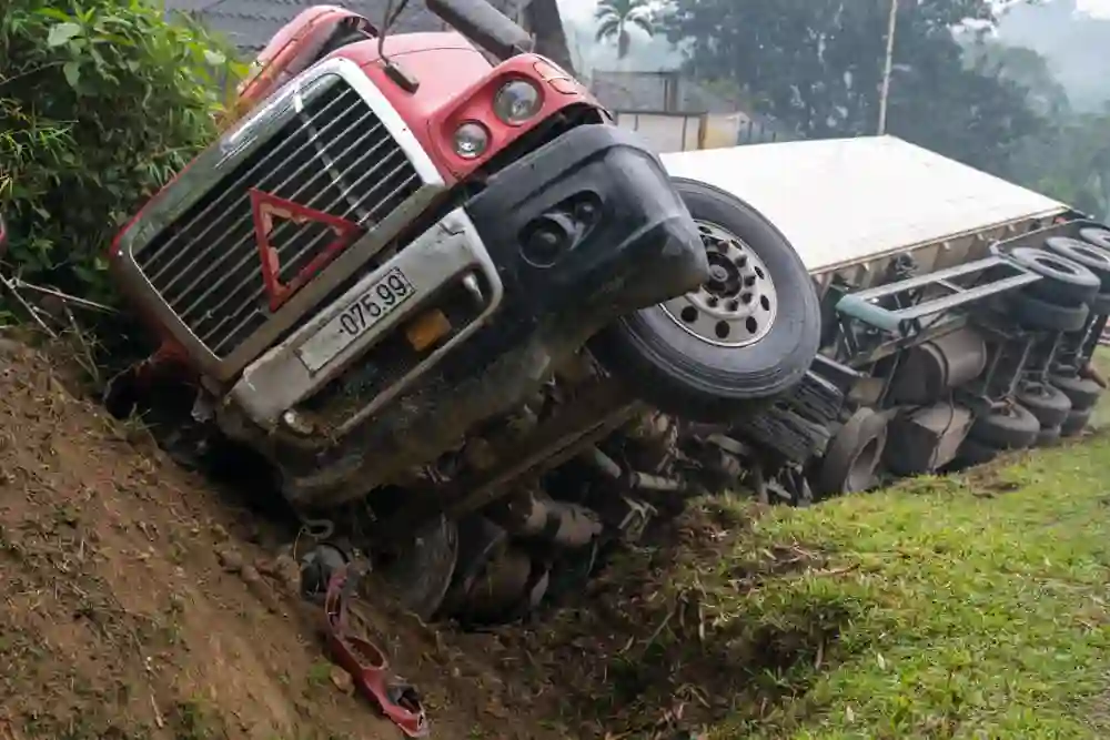 Truck accident on mountain road, overturned vehicle lying in ditch on its side, motor vehicle wreck