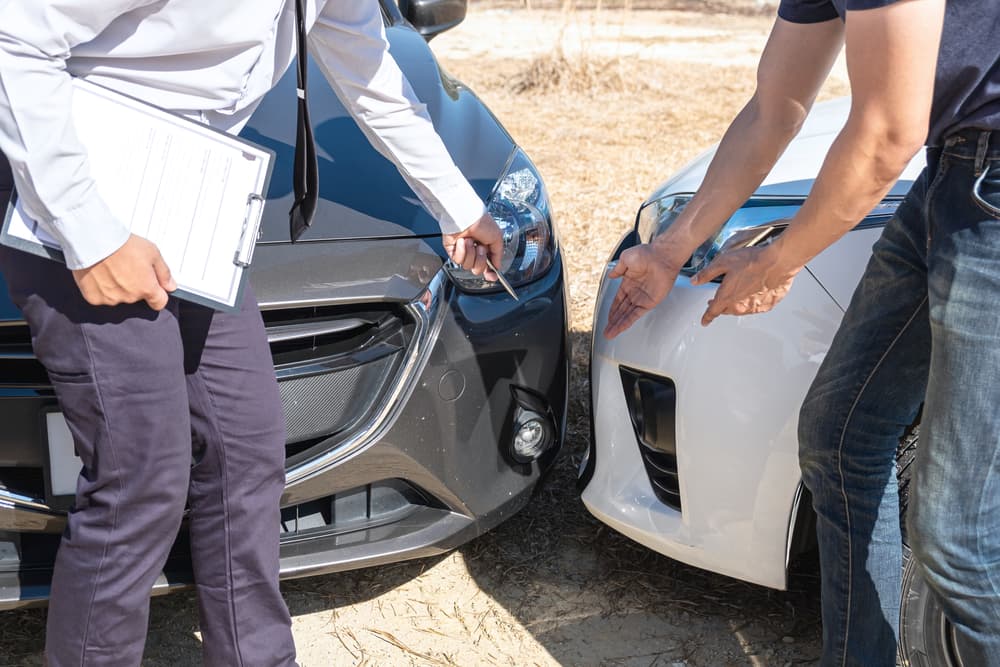 Insurance agent examine the damage of the car after accident on report claim form process.