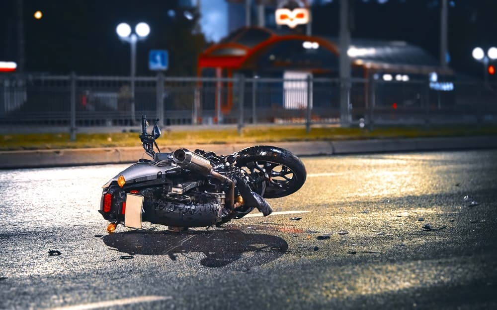 Motorcycle lying on asphalt after an road accident. Moto bike collision at night.