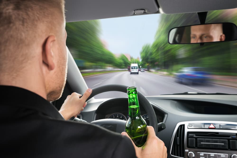 Rear View Of A Businessman Drinking Beer While Driving Car