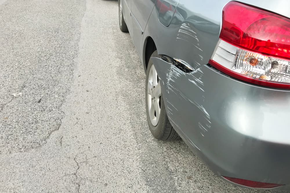 Backside of silver car get damaged by accident.